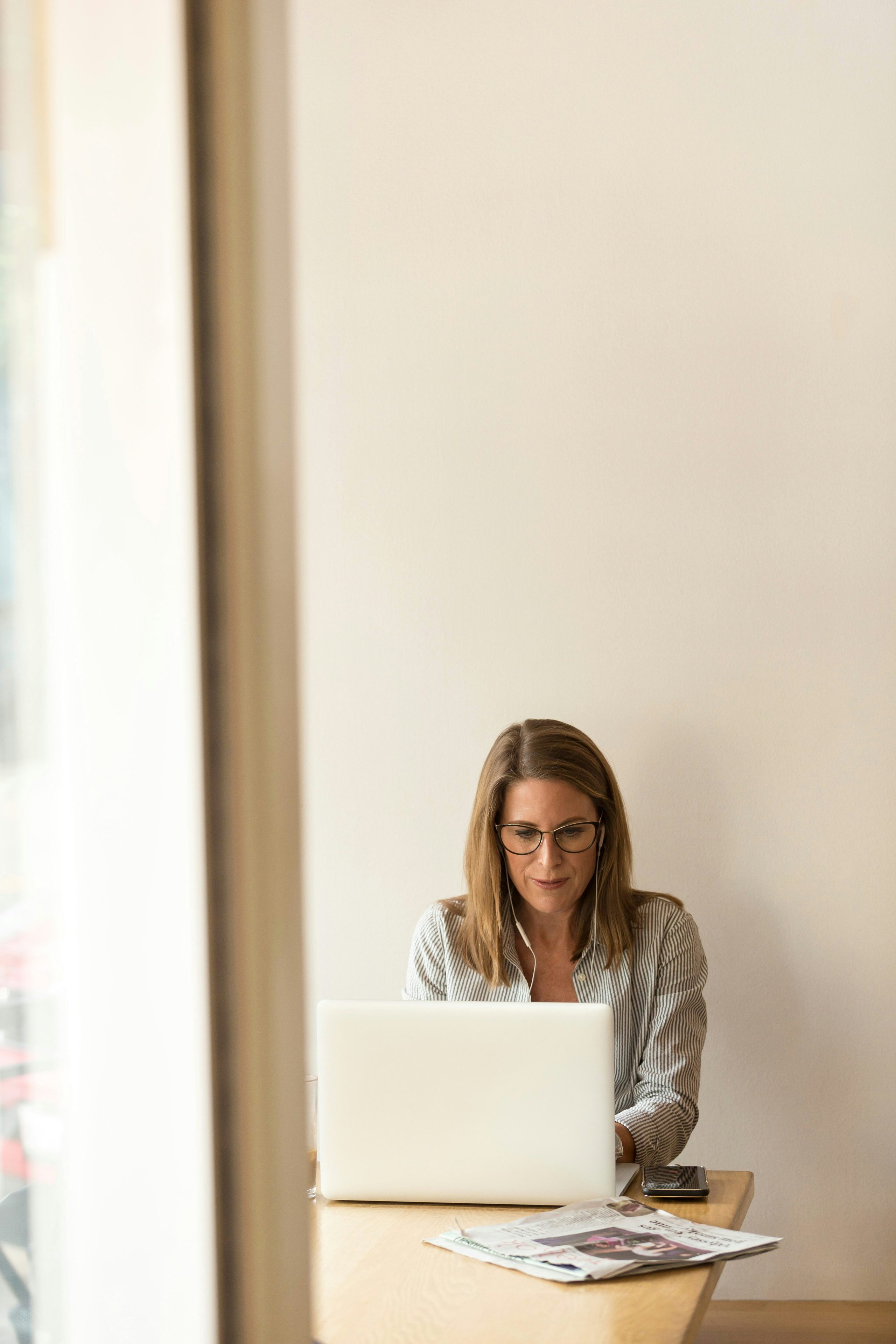 A woman in glasses with coffee and a laptop at home