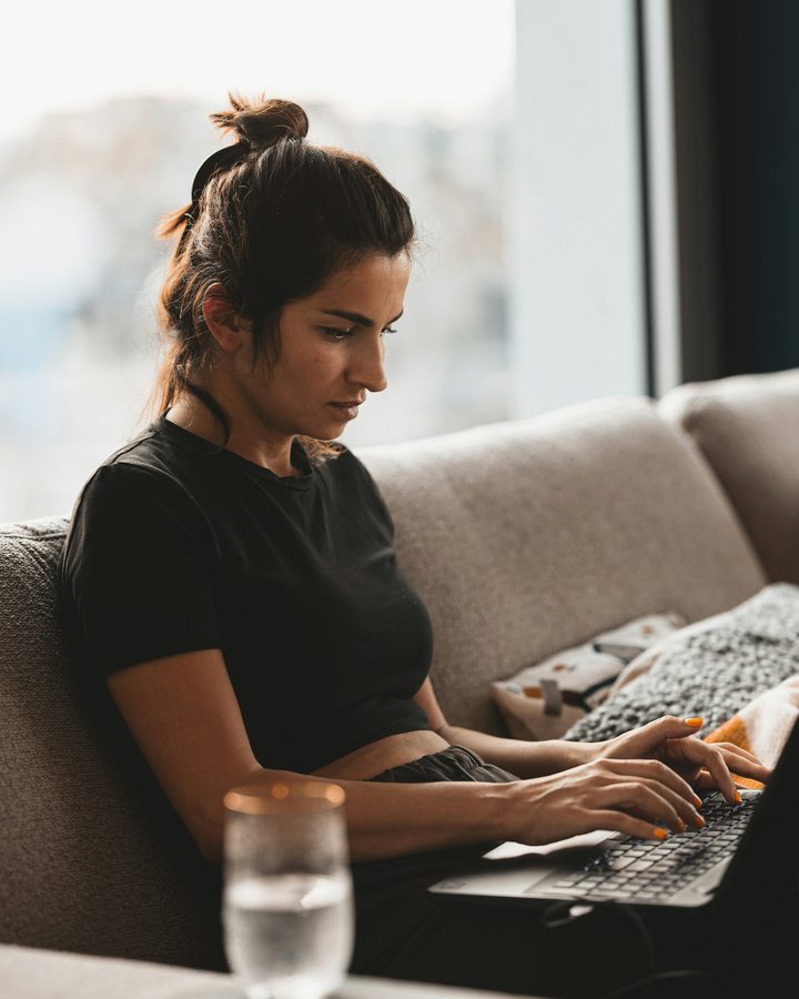 Γυναίκα δουλεύει στο laptop της, στον καναπέ